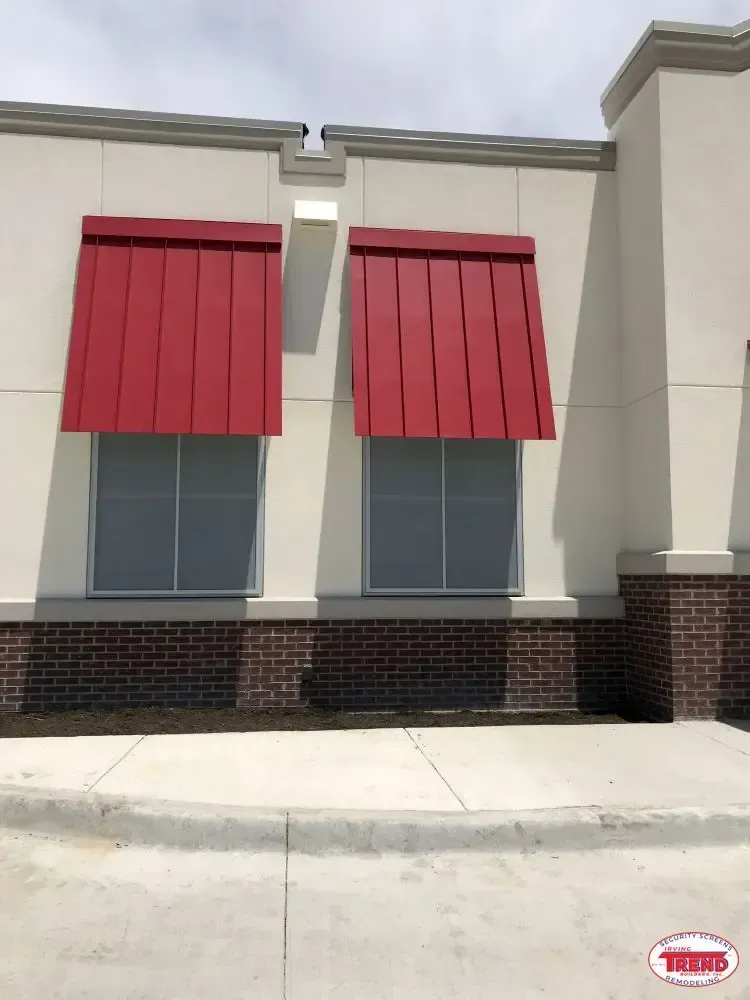 A white building with red awnings on the windows