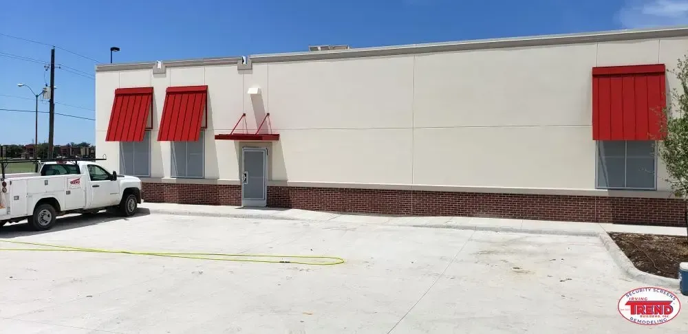 A white truck is parked in front of a building with red awnings.