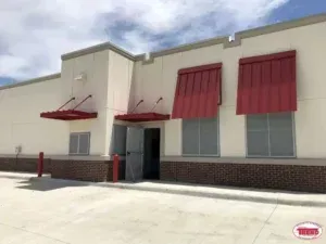 A white building with red awnings on the windows.