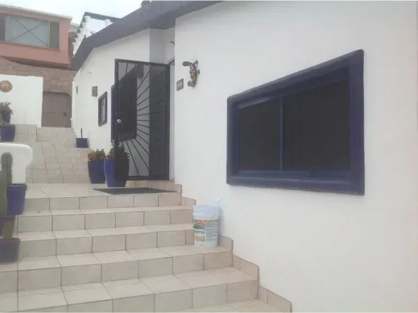 A white house with a blue window and stairs