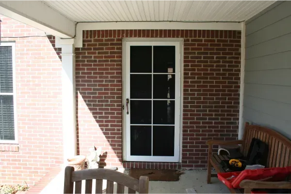 A porch with a brick wall and a screen door