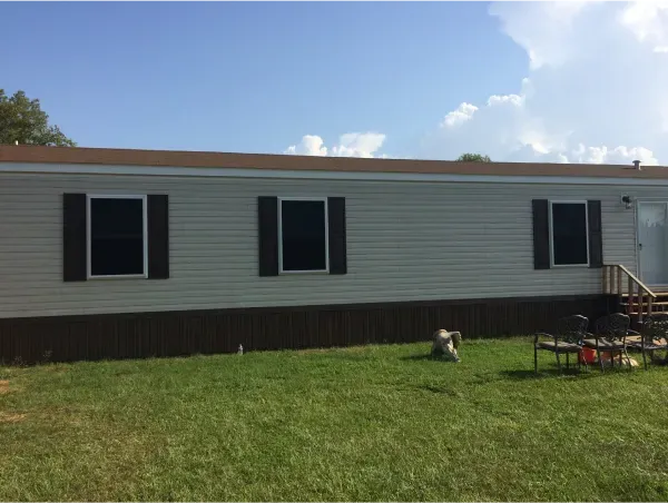 A white mobile home with black shutters on the windows