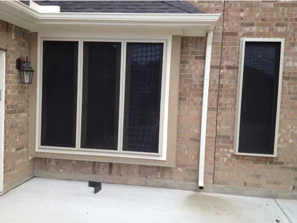 A brick house with a large window and two smaller windows