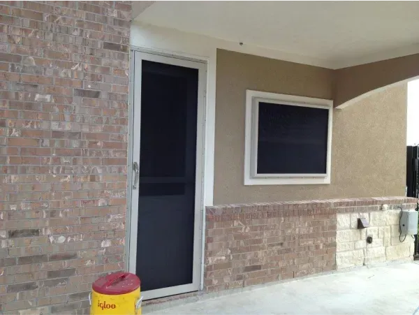 A brick building with a screen door and a window