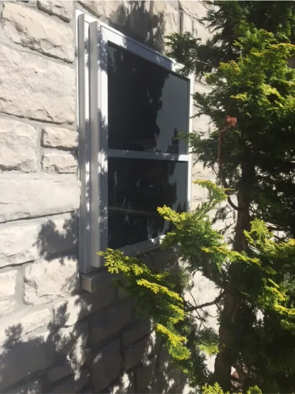 A window on a brick wall next to a tree