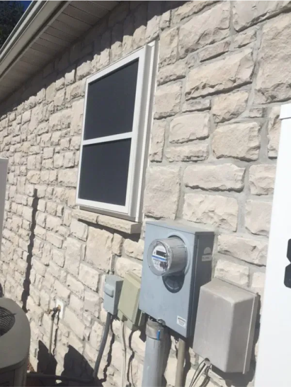 A brick wall with a window and a meter on it