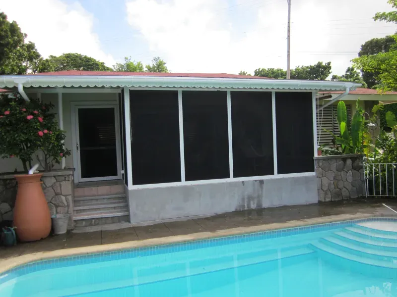 A screened in porch with a swimming pool in front of it