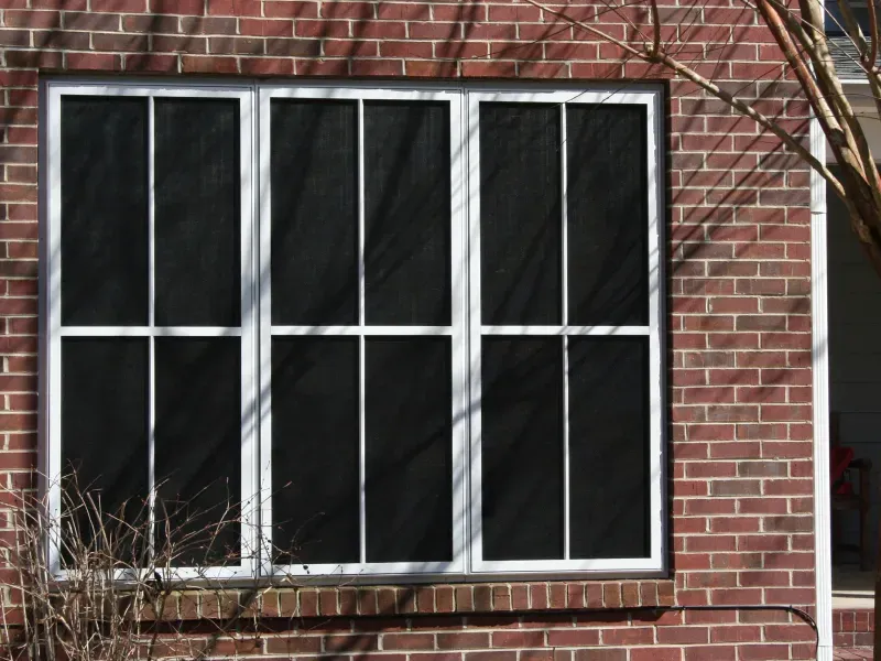 A brick building with a window with black screens