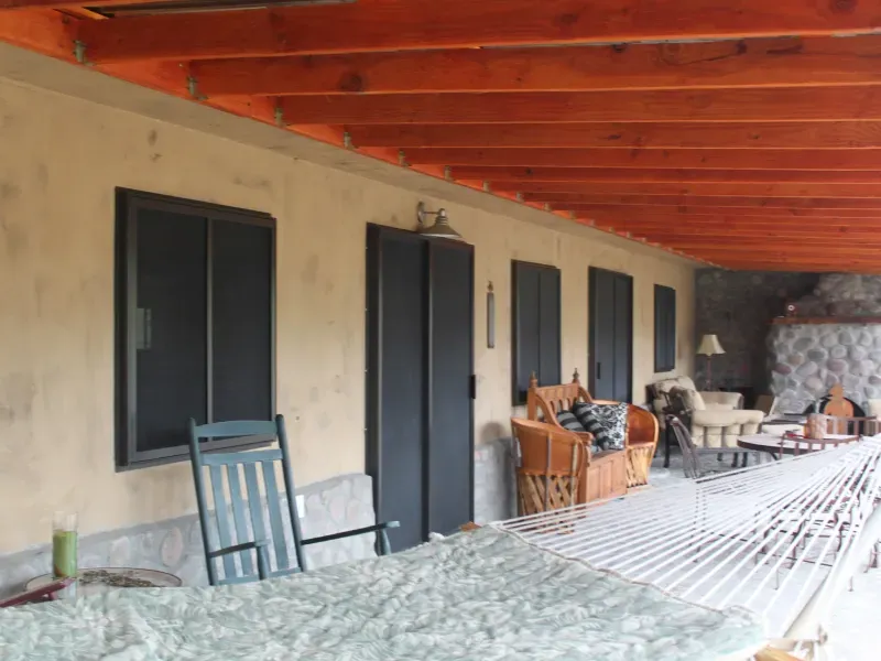 A porch with chairs and a table under a wooden ceiling
