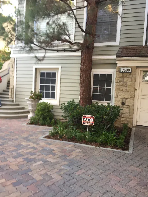 A house with a tree in front of it and a sign in front of it.
