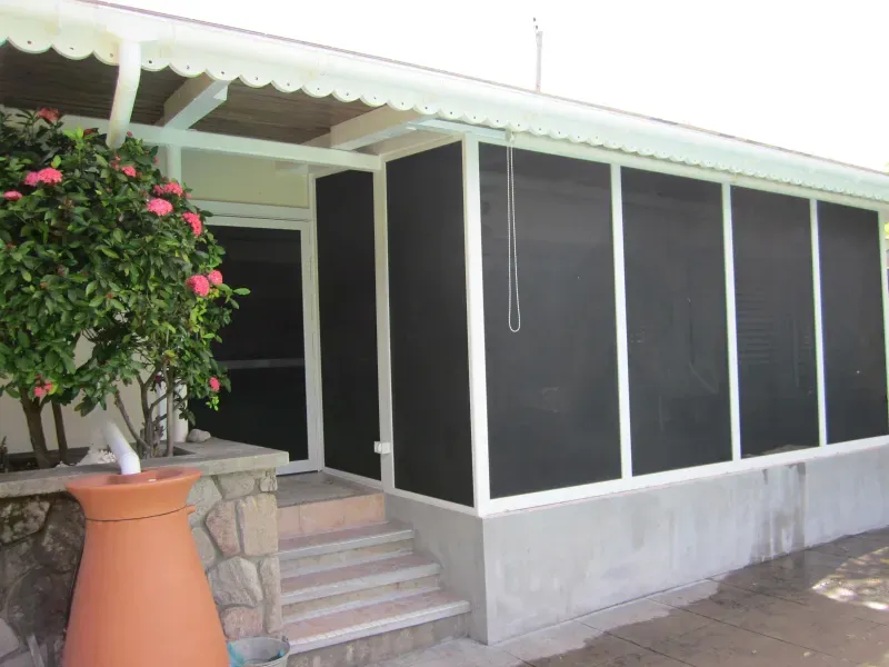 A screened in porch with a potted plant in front of it
