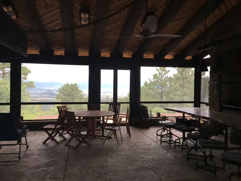 A screened in porch with tables and chairs and a view