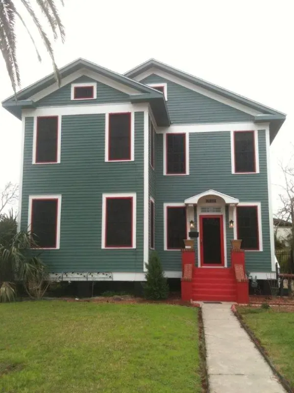 A green house with white trim and red stairs