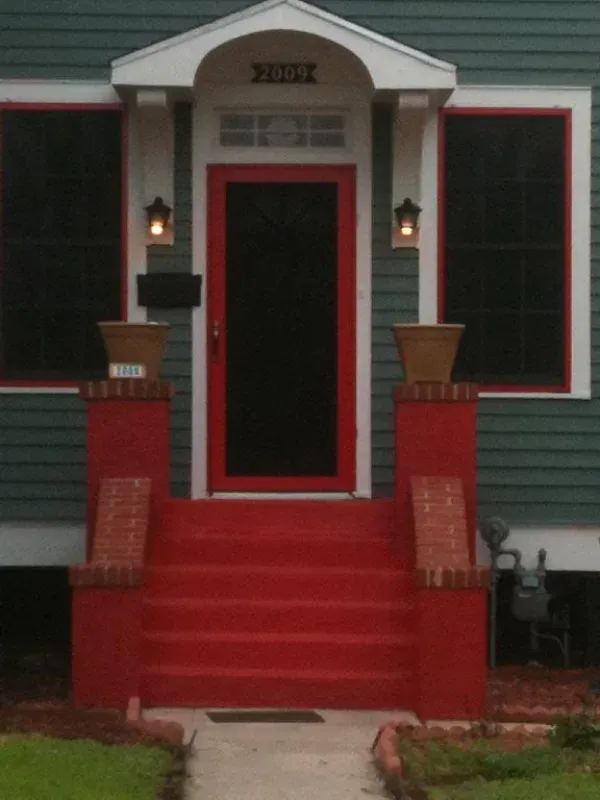 A green house with a red front door and steps