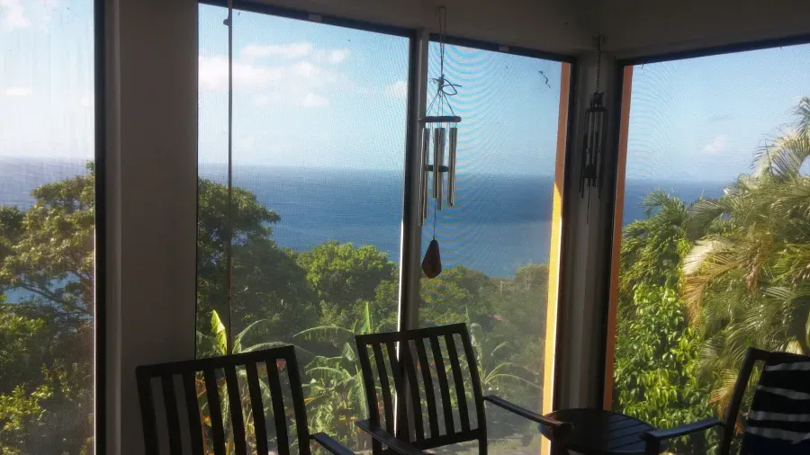 A room with two chairs and a table with a view of the ocean.