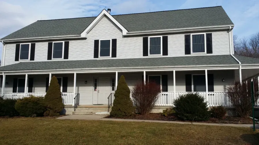 A large white house with a gray roof and black shutters
