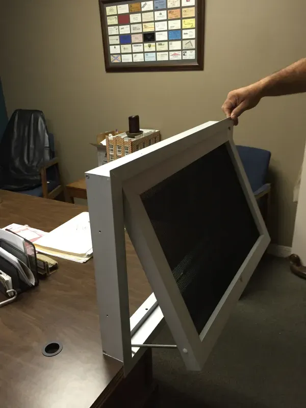 A person is holding a computer monitor on a desk