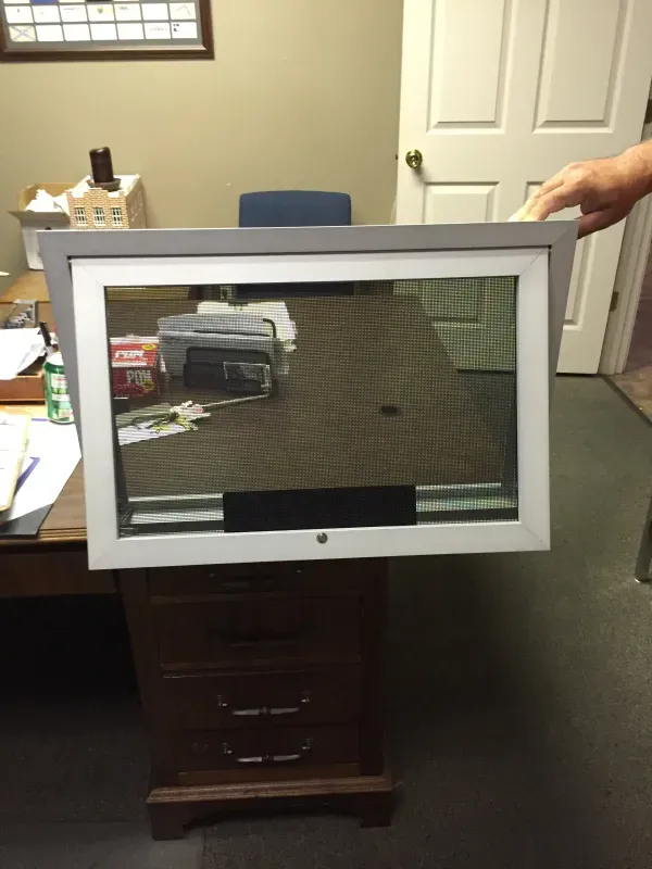 A person is holding a picture frame over a desk