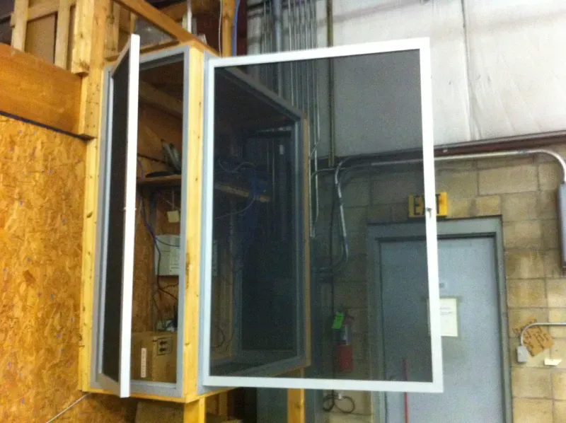 A screen door is open in a room next to a door.