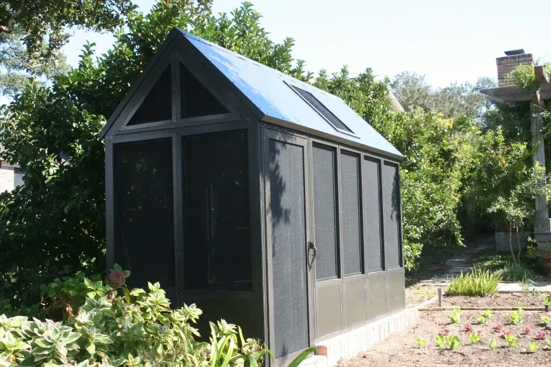 A black screened in shed with a blue roof