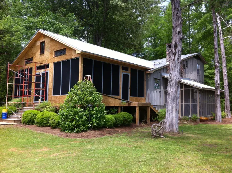 A house with a screened in porch is being built in the woods.