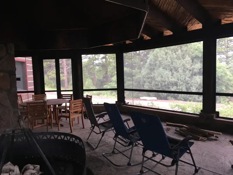 A screened in porch with rocking chairs and tables
