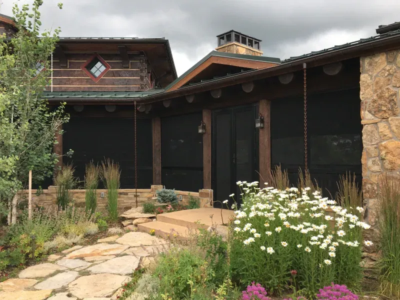 A house with a screened in porch and flowers in front of it.