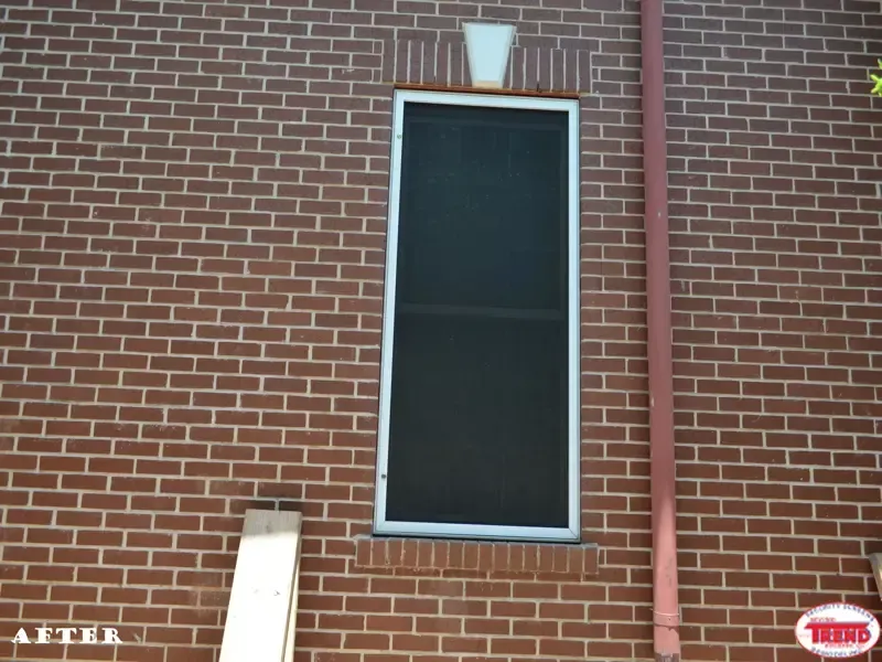 A picture of a brick building with a screened in window
