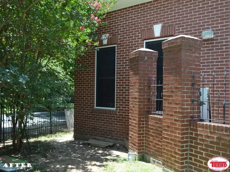 A brick building with a fence and a tree in front of it