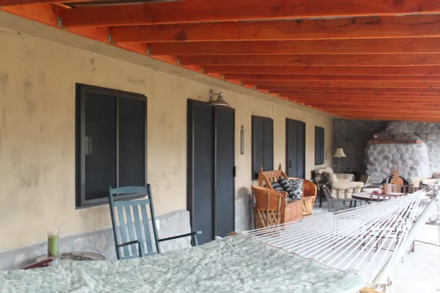 A porch with a table and chairs under a wooden roof
