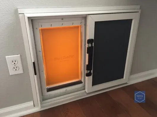 A dog door is built into a wall in a room.