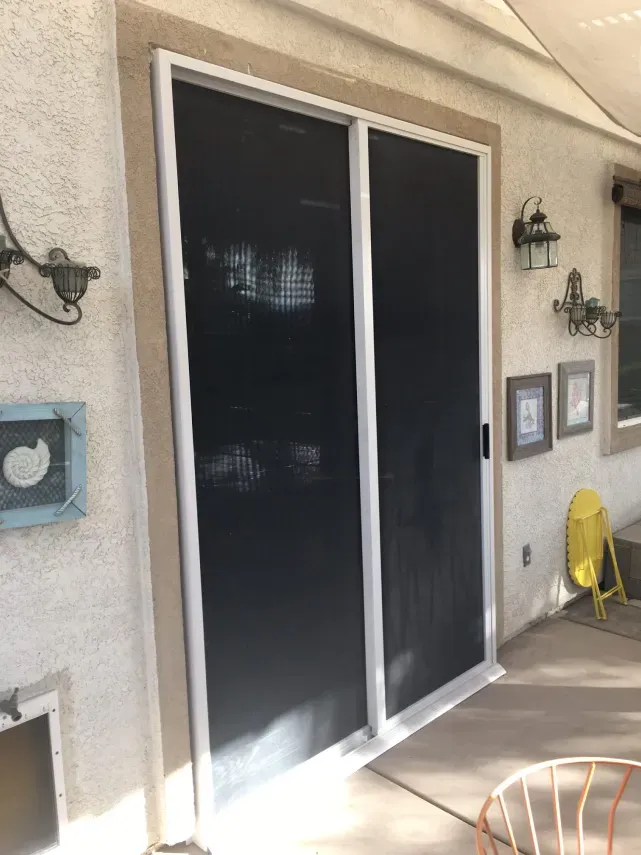 A patio with sliding glass doors and a yellow chair.