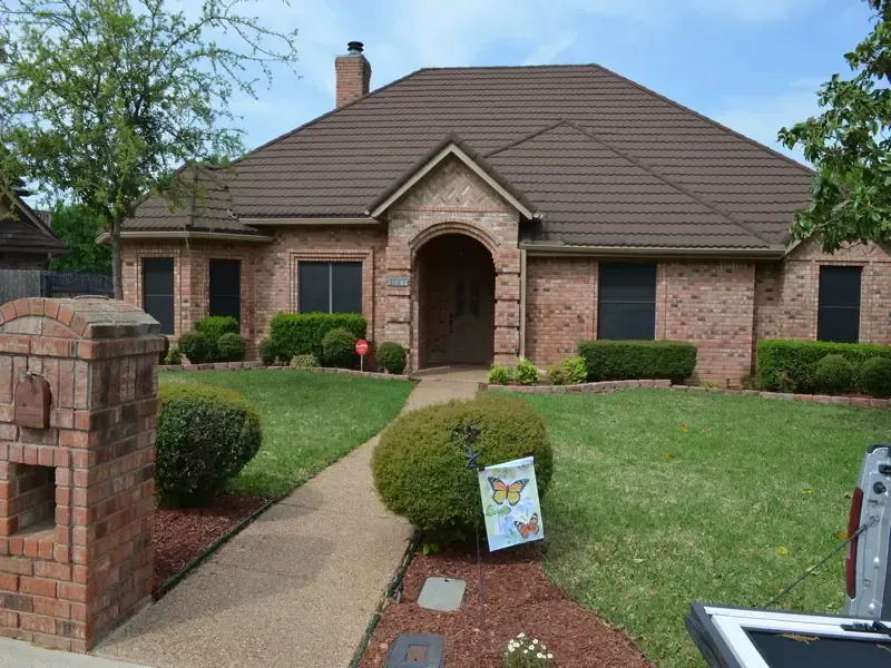 A brick house with a brown roof and a mailbox