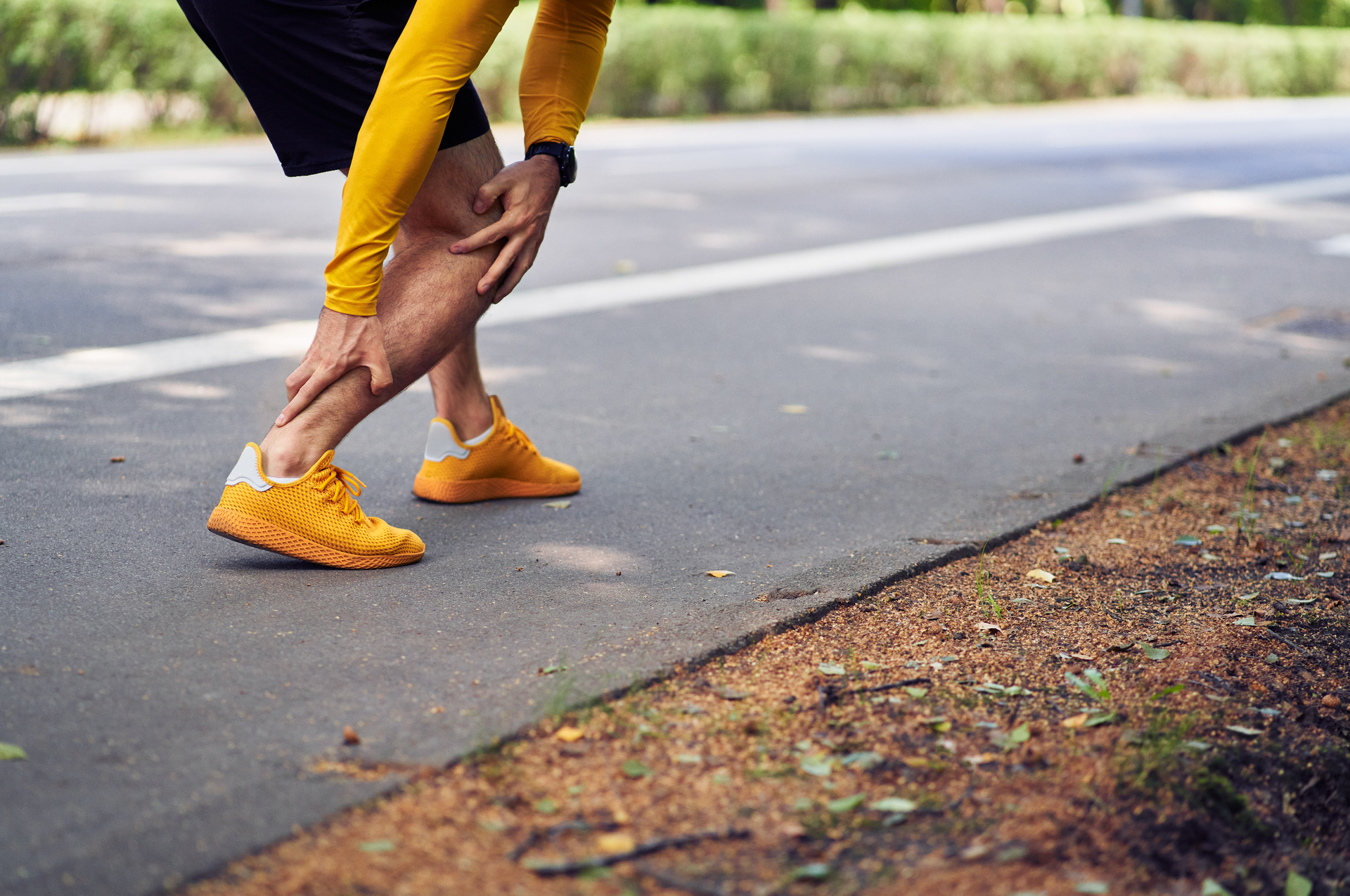 Runner stretching and holding Achilles tendon on road