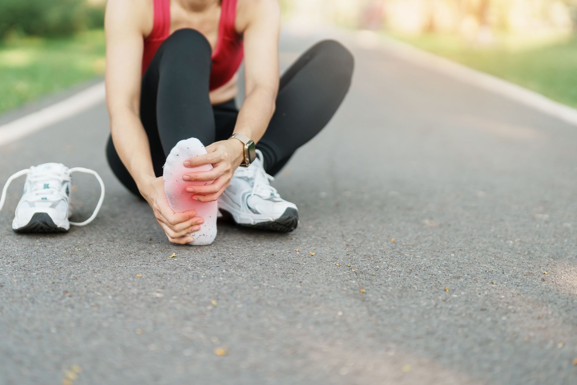 Runner sitting on road holding painful foot