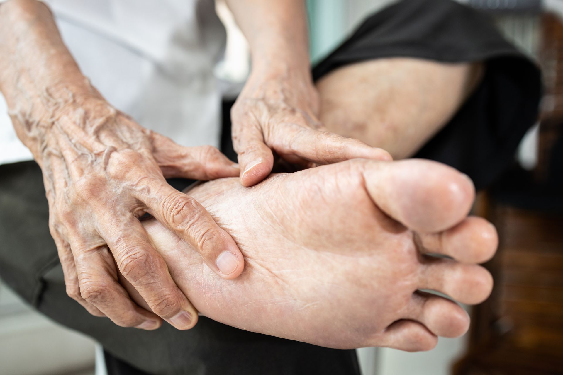 Older adult holding foot due to discomfort
