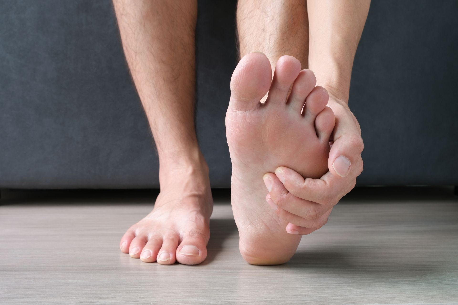 Person holding bottom of foot due to heel pain