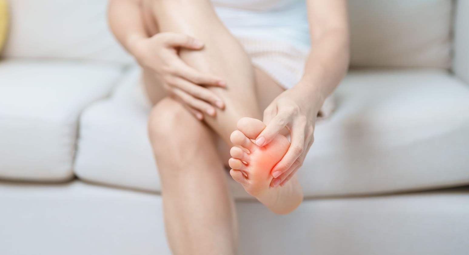 Person sitting on couch holding forefoot with pain highlight