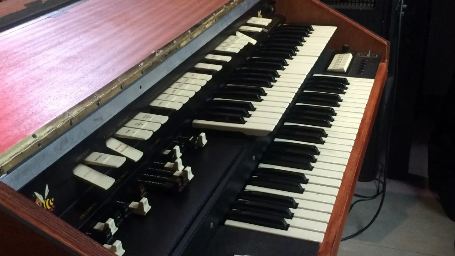 Vintage Hammond organ with two keyboards and drawbars, brown and black tones.