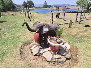 A statue of an elephant standing next to a potted plant in a park.