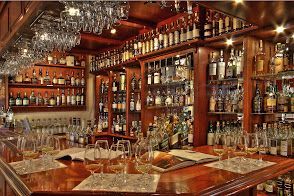 A bar filled with lots of wine bottles and glasses.