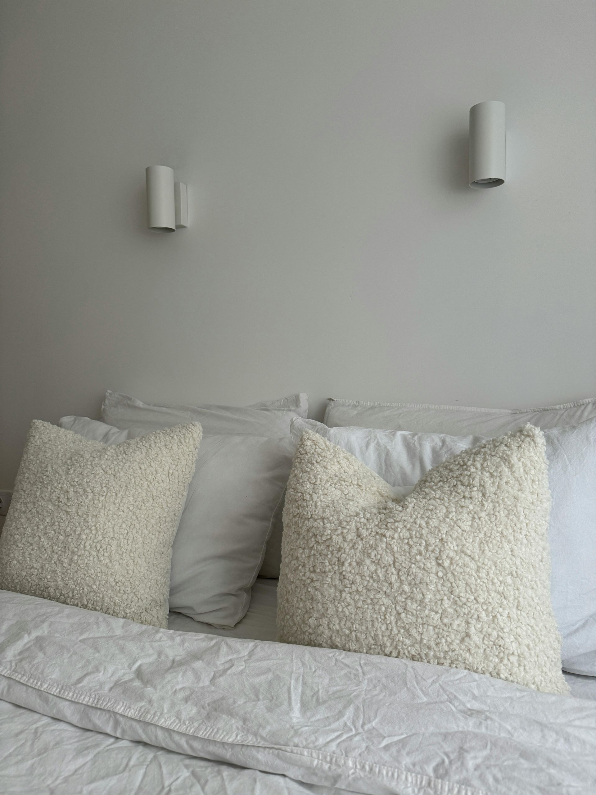 A bed with white sheets and pillows in a bedroom.