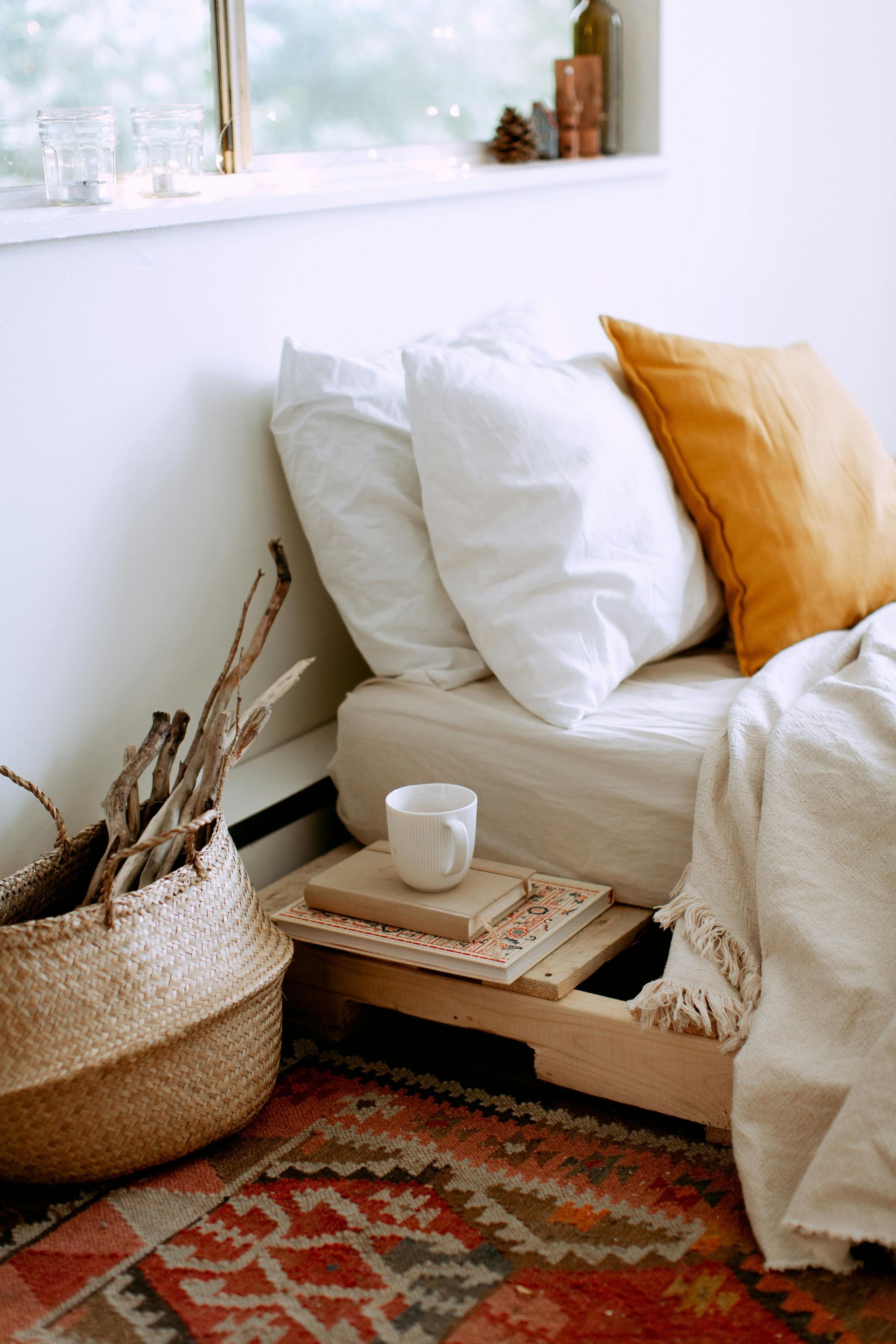 A bed with white sheets and pillows in a bedroom next to a window.