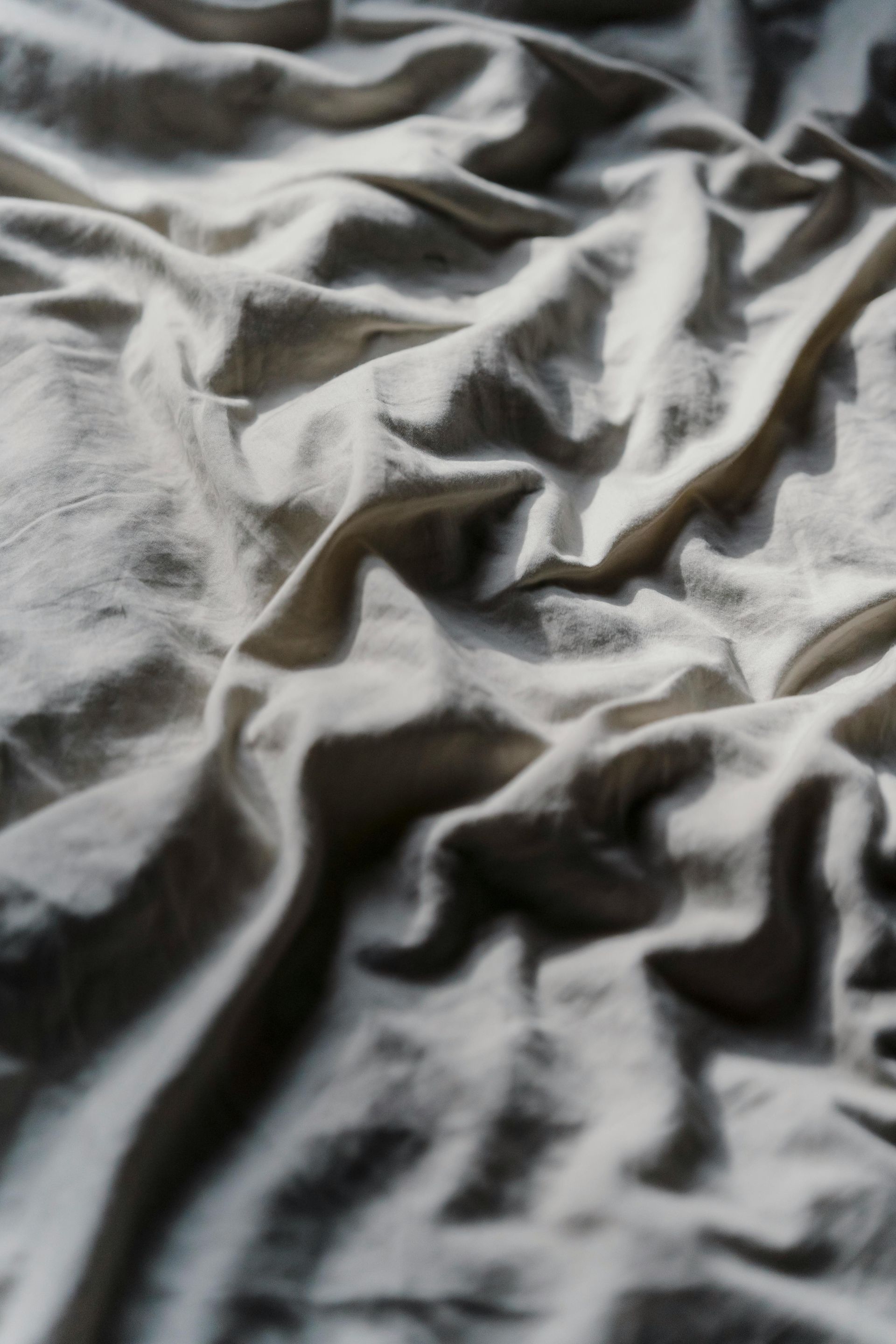 A close up of a white blanket on a bed.