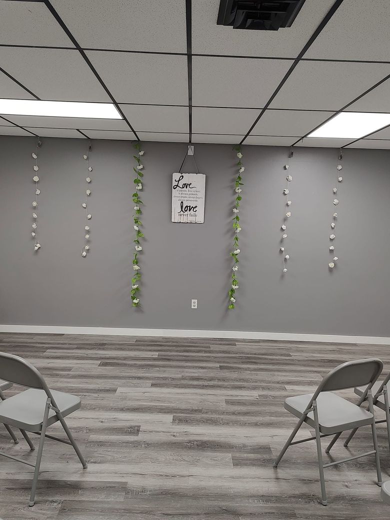 Decorated meeting room with hanging paper garlands, gray walls, folding chairs, and a wood-pattern floor