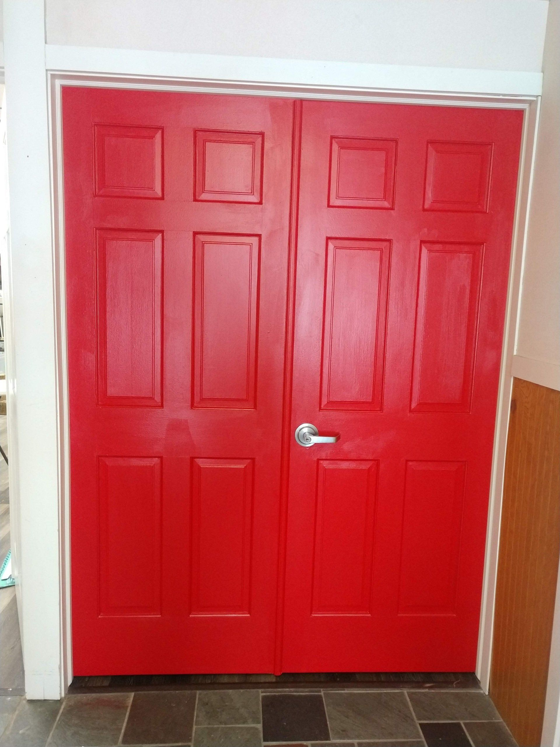 Red double interior door with silver handle against white walls