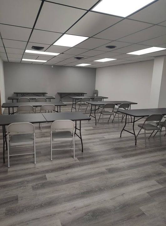 Empty classroom with rows of desks and chairs under fluorescent ceiling lights