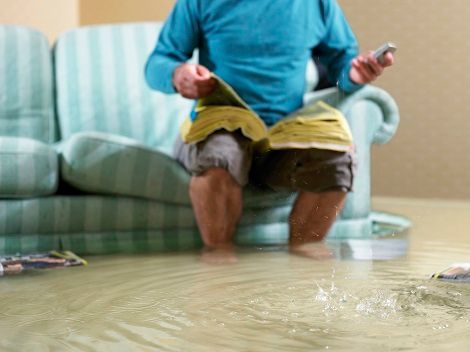 Man Sitting in Flooded Living Room Using Phone, Low Section | St. Pete Beach, FL - Damage Control Co