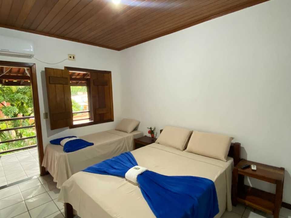 Um quarto de hotel com duas camas, teto com ripas de madeira e uma porta que dá para uma varanda externa.