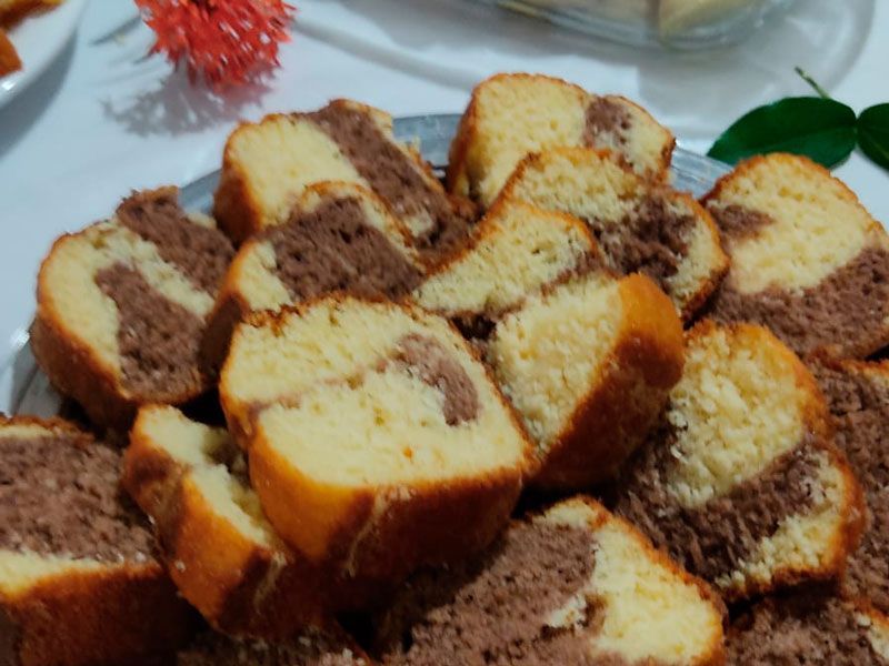 Uma visão aproximada de fatias de bolo mármore com padrões em espiral de bolo amarelo e chocolate em uma bandeja de prata.